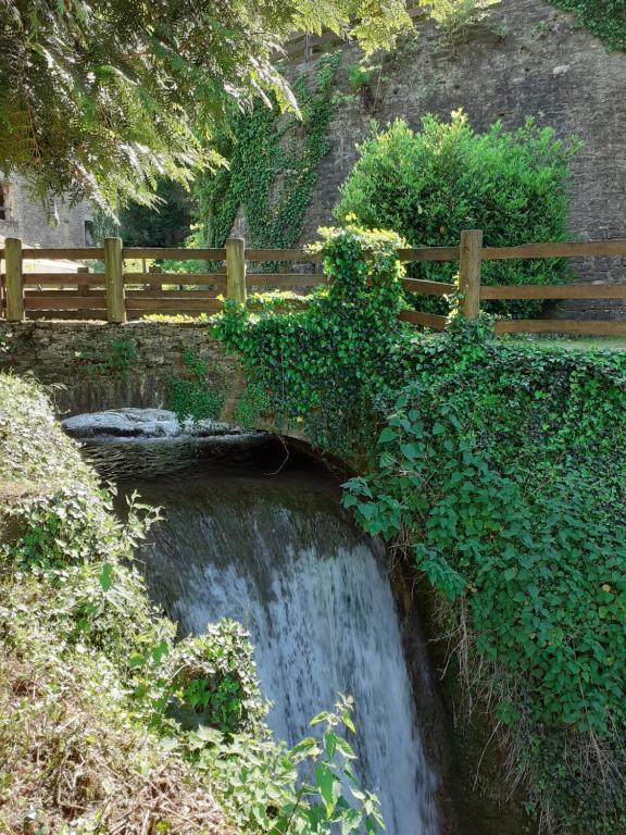 un puente sobre una cascada con una valla de madera en Moulin Chantepierre en Pont-dʼHéry