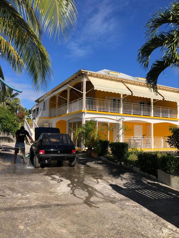 a car parked in front of a yellow house at Ti Kaz À Patou, au coeur de l'île. in Baie-Mahault
