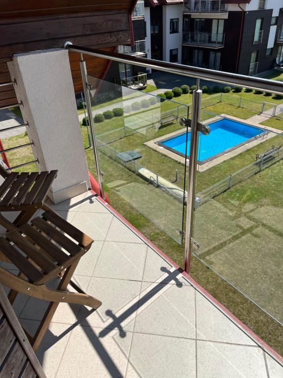 a balcony with a chair and a swimming pool at Apartament Lisi Jar in Jastrzębia Góra