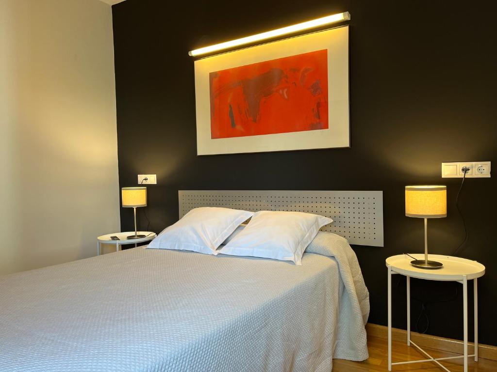 a bedroom with a bed and two tables with lamps at Apartamentos León in León