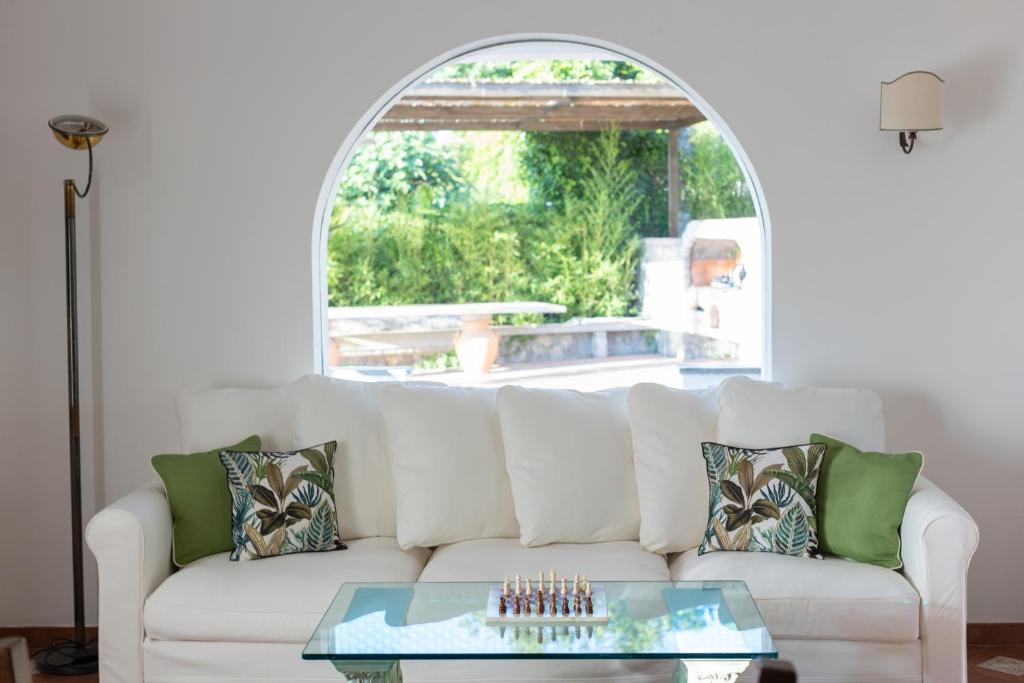 a living room with a white couch with a glass table at Villa Aurora Pool & Fitness in Anacapri