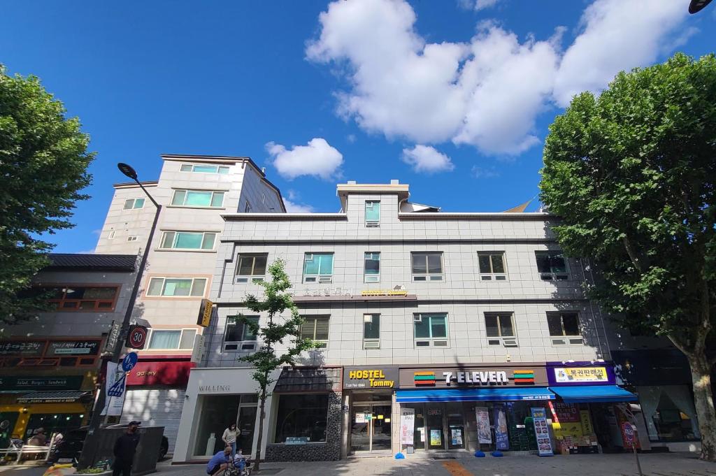 un grand bâtiment blanc dans une rue de la ville dans l'établissement Hostel Tommy, à Séoul