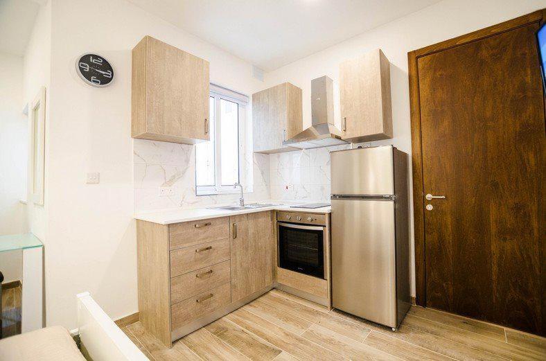 a kitchen with a stainless steel refrigerator and wooden cabinets at Valletta Republic Suite in Valletta