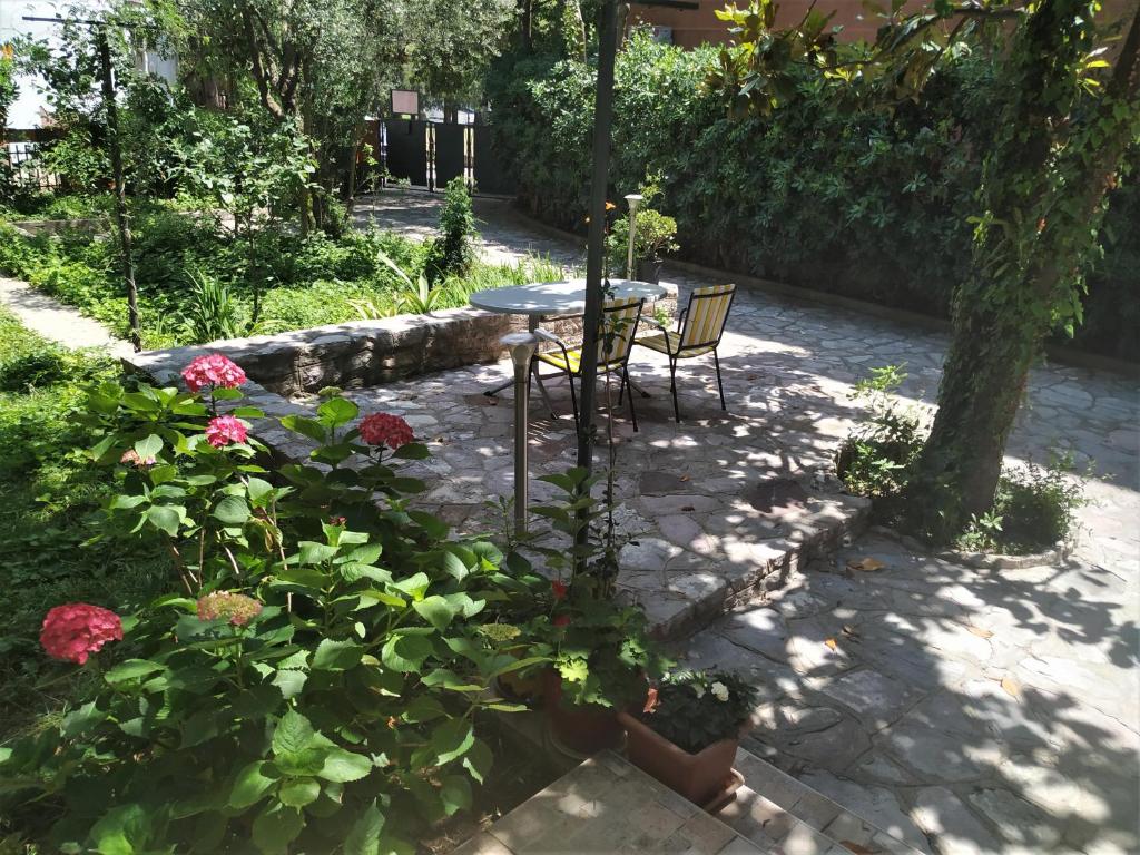 un patio con mesa, sillas y flores en Apartmani Abeona, en Budva