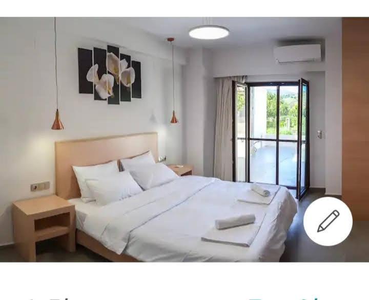 een slaapkamer met een groot wit bed en een raam bij Kamilos apartments in Monastirákion