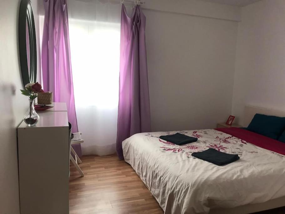 Schlafzimmer mit einem Bett und einem Fenster mit lila Vorhängen in der Unterkunft A lovely 2 bedroom apartment near Sintra in Lissabon