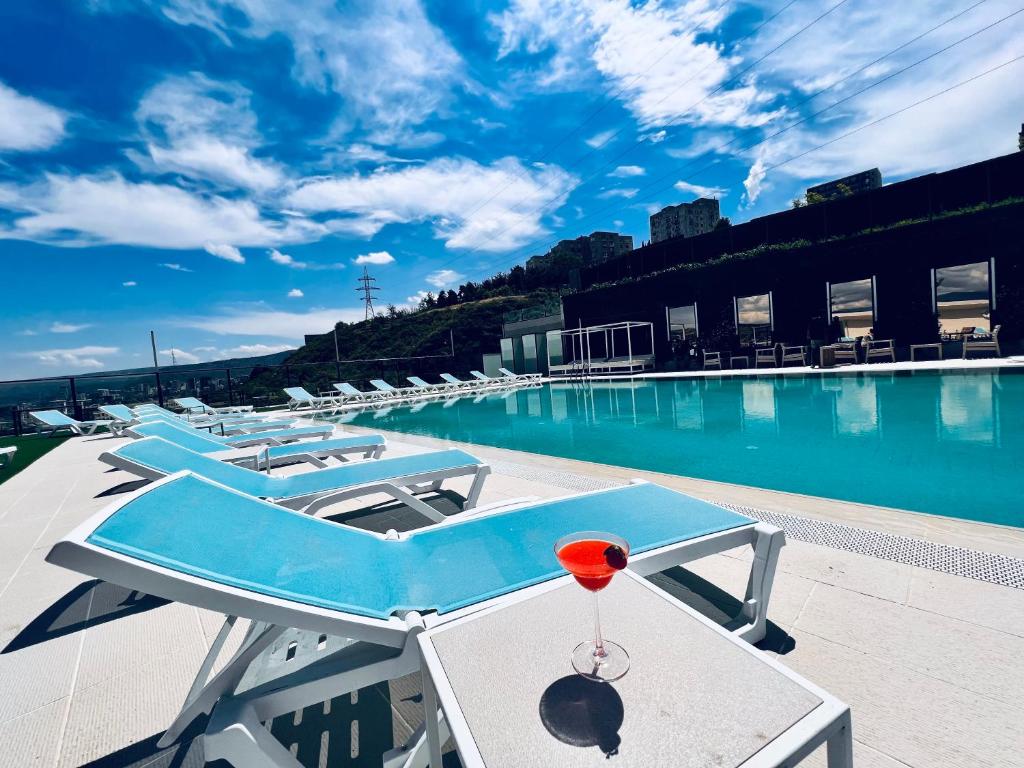 a swimming pool with a table with a drink on it at Hotel Beaumonde Garden in Tbilisi City