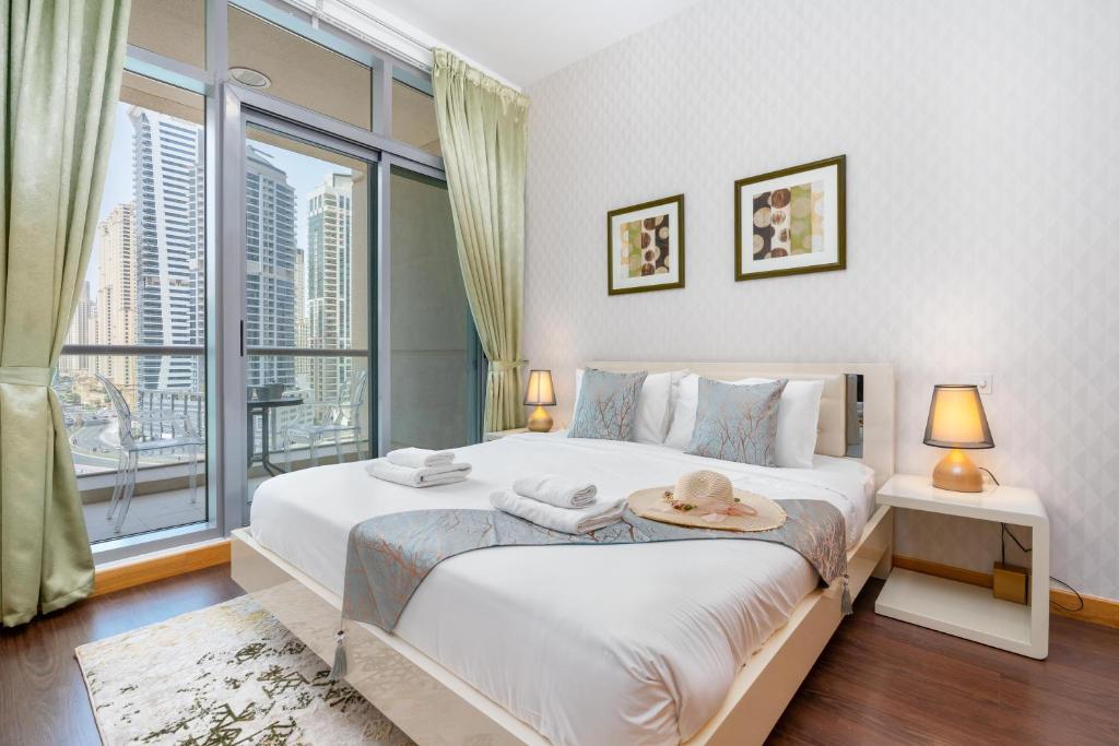 a bedroom with a large bed with a large window at Vacay Lettings - 1 Bed at Iris Blue, Dubai Marina in Dubai