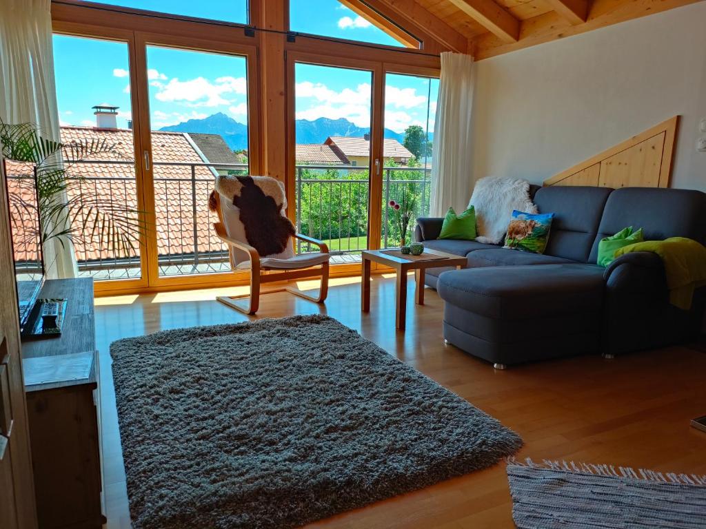 a living room with a couch and a large window at Ferienwohnung Alpenlodge in Rieden am Forggensee