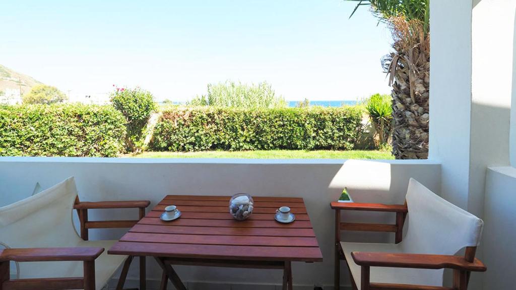 a wooden table and two chairs on a patio at Ενοικιαζόμενα Διαμερίσματα Άρτεμις in Skiros