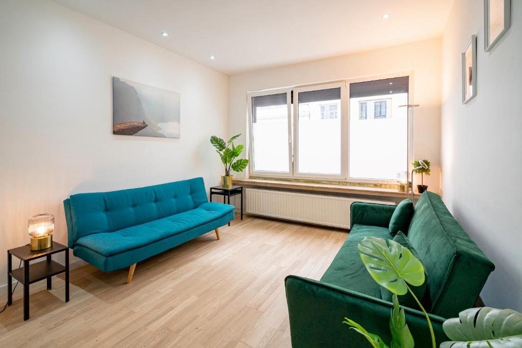 a living room with a blue couch and two chairs at Charming Central Cityflats in Antwerp