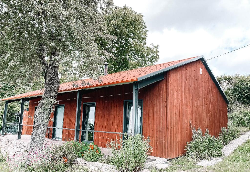 ein rotes Haus mit einem Baum davor in der Unterkunft Oficina do Joe , Bungalow Gitte in Outeiro