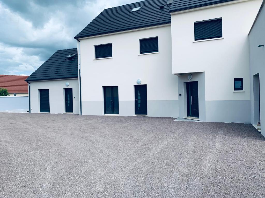 een wit huis met zwarte deuren en een oprit bij Duplex, parking gratuit privé, 5min centre Auxerre in Monéteau