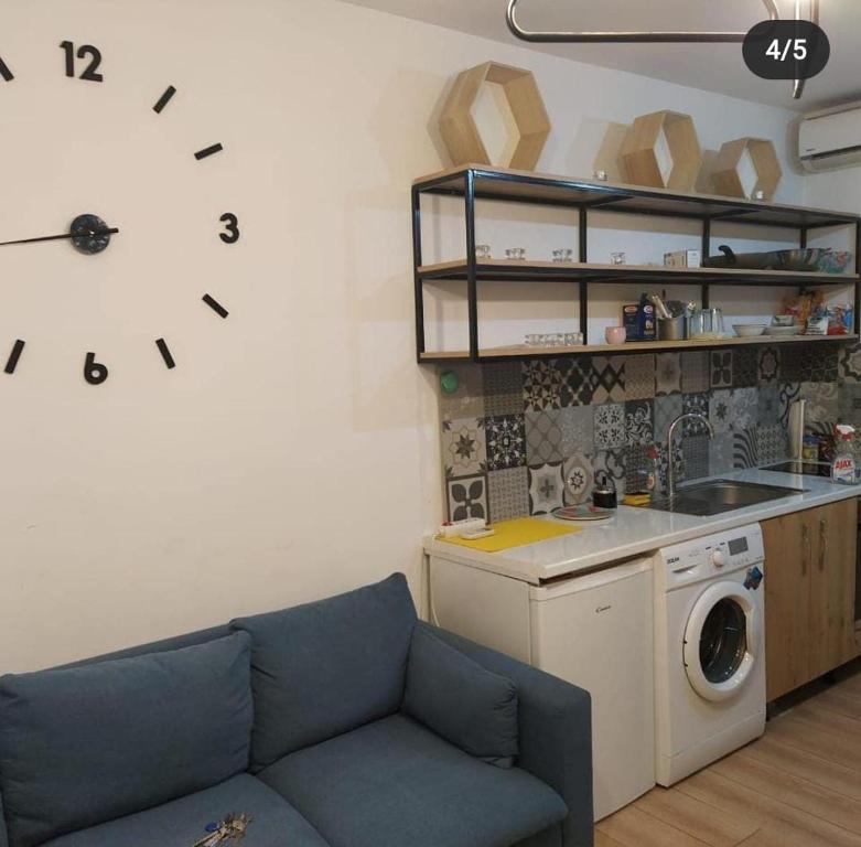 een woonkamer met een bank en een klok aan de muur bij Lovely 1 bedroom apartment near Eye of Tirana in Tirana