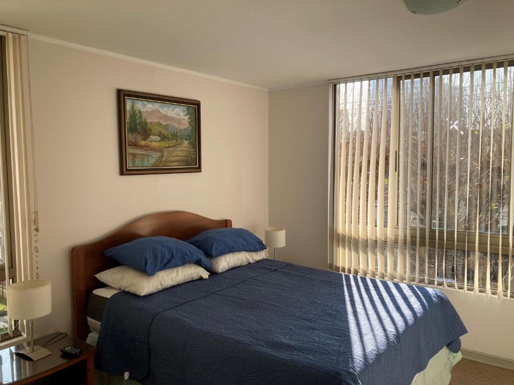 1 dormitorio con cama con sábanas azules y ventana en Departamento Viña del Mar, en Viña del Mar