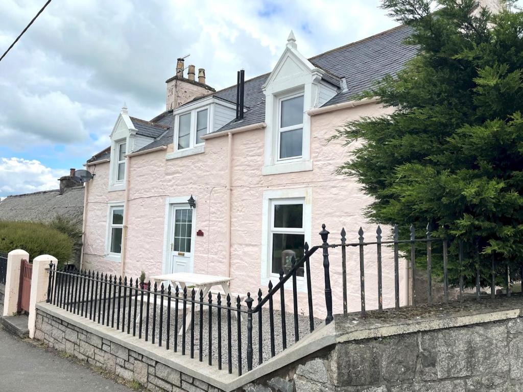 a pink house with a fence in front of it at Pass the Keys Spacious 3BR Cottage in Beautiful Rural Setting in Castle Douglas