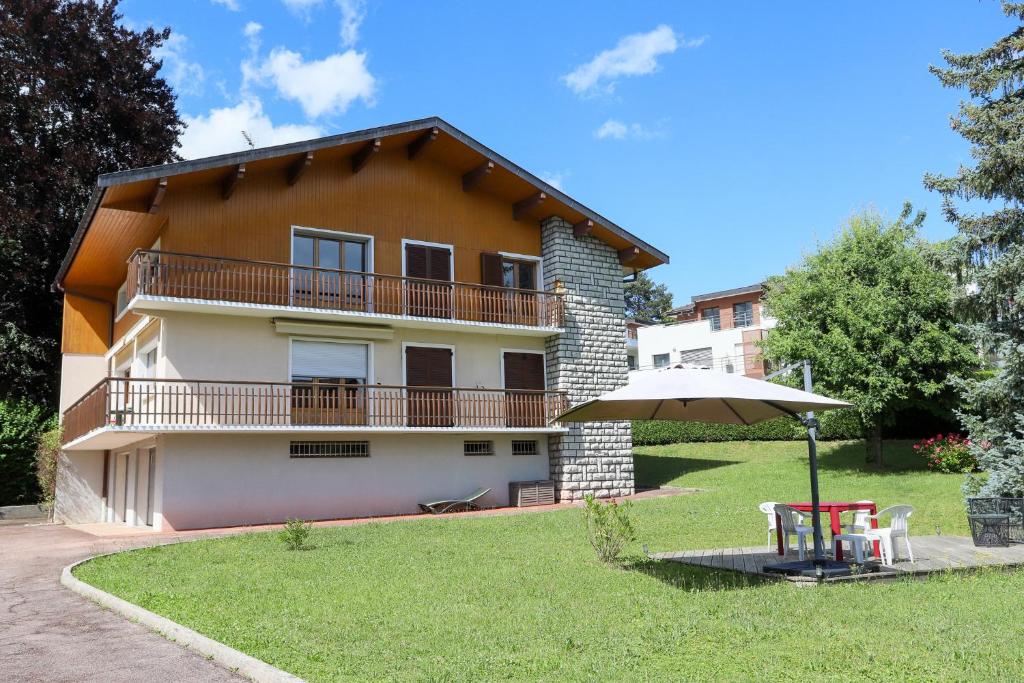 a house with an umbrella and a table in the yard at Le Vintage grand appartement 4 étoiles avec jardin proche du lac in Annecy