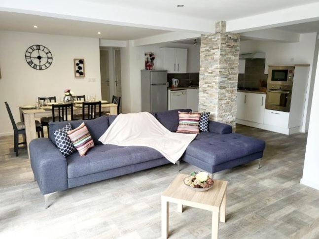 a living room with a blue couch and a kitchen at Loft du sud ouest av garage in Laplume