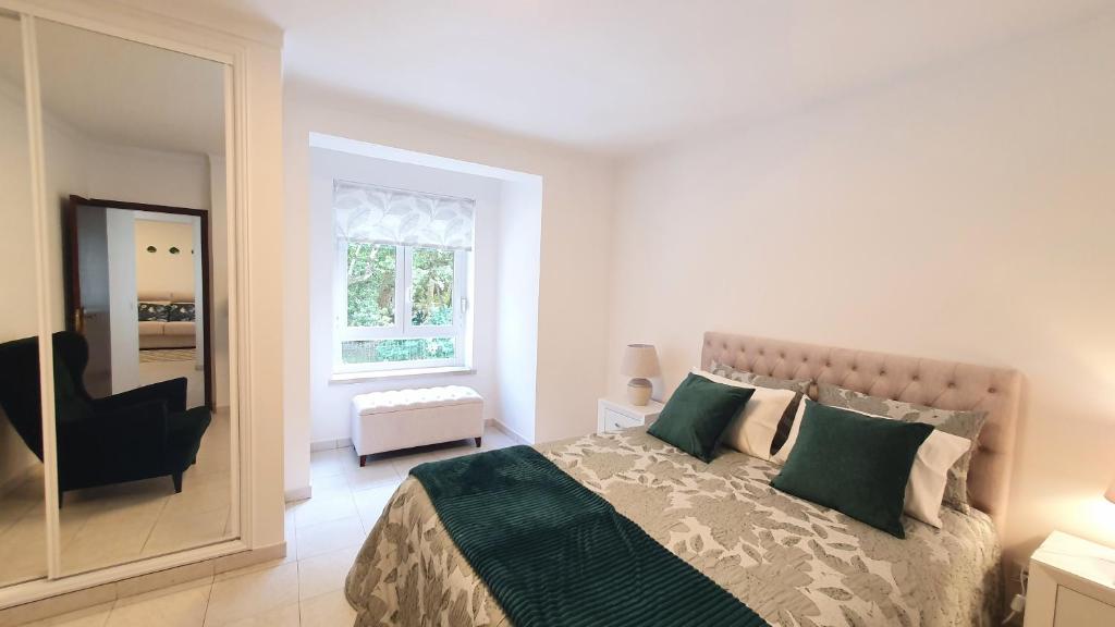 a bedroom with a bed and a chair and a mirror at Caldas da Rainha's Green & White in Caldas da Rainha