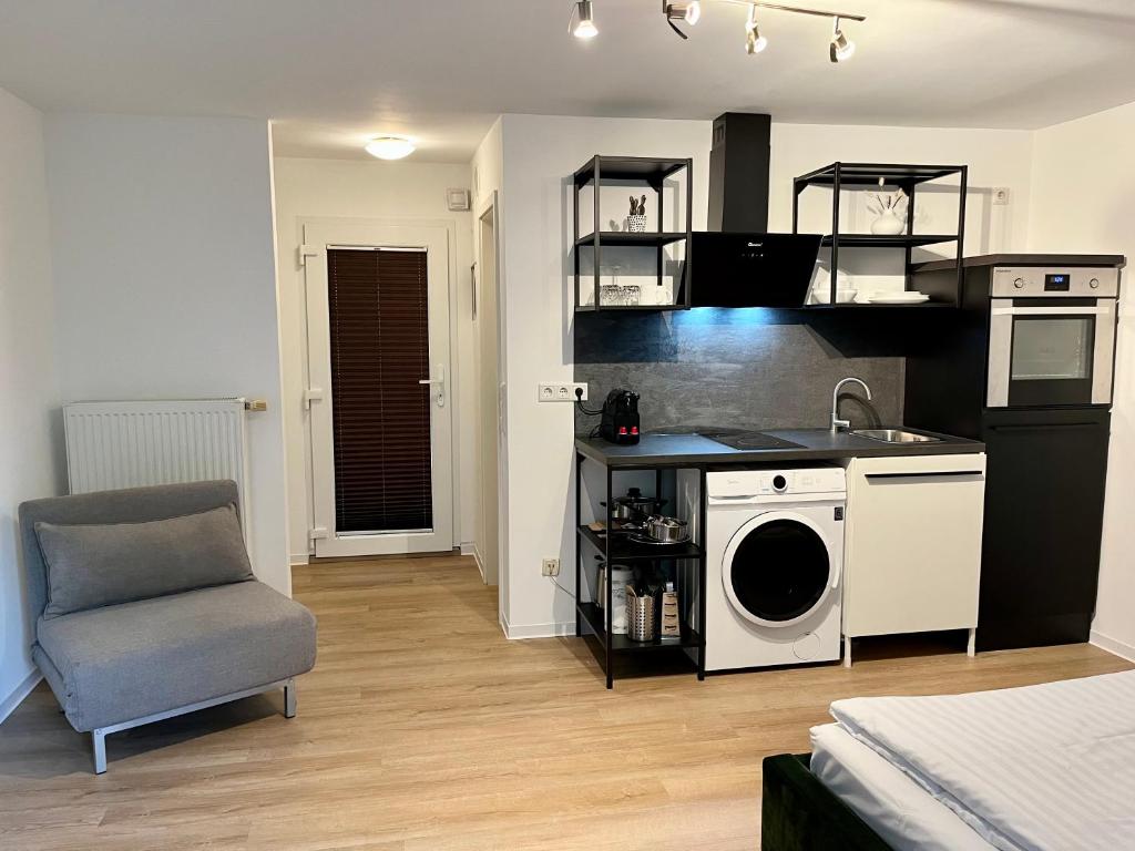 a kitchen with a washing machine and a chair at Ferienwohnung Washingtonweg in Hannover