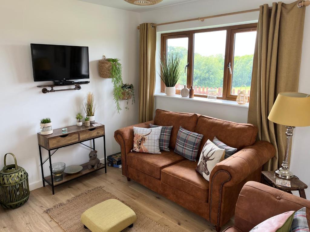 a living room with a brown couch and a tv at Oak Valley Lodges in Pett