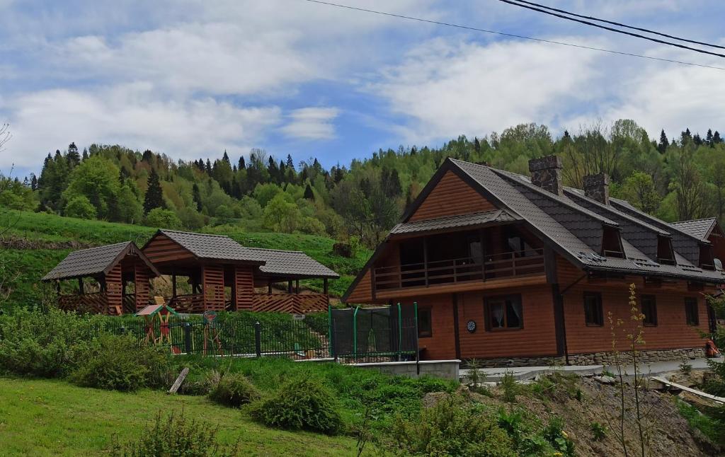two wooden houses in a field with trees in the background at Сімейний Затишок апартаменти in Oryavchyk