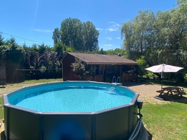 a large swimming pool in a yard with an umbrella at La Zénitude petit coin de détente proche de Sarlat in Berbiguières