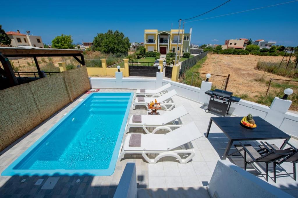 a patio with a pool and a table and chairs at Kremasti Pool Villa near the beach in Kremasti
