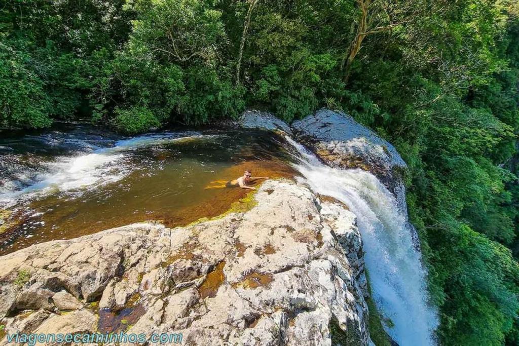 una persona nadando en una cascada sobre una roca en Pousada Três Forquilhas, en Guananazes