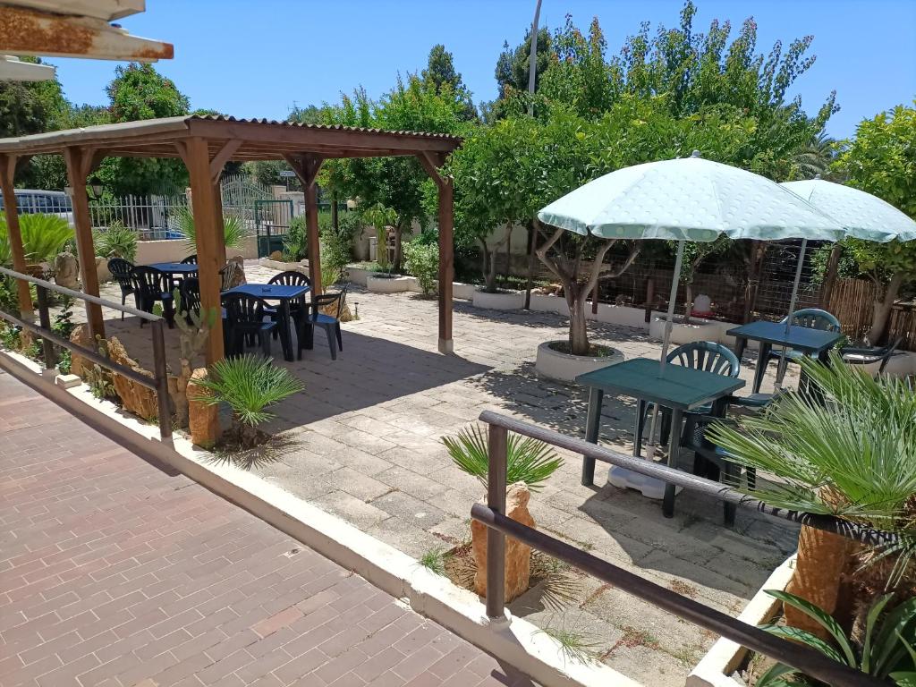 un patio con mesas, sillas y una sombrilla en Mony's Island B&B en Alguer