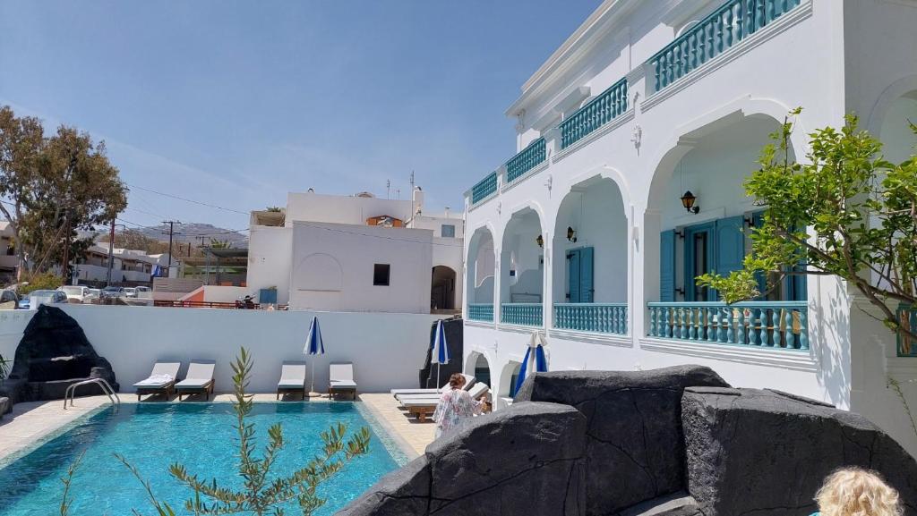 a woman sitting next to a swimming pool next to a building at Armonia in Kamari