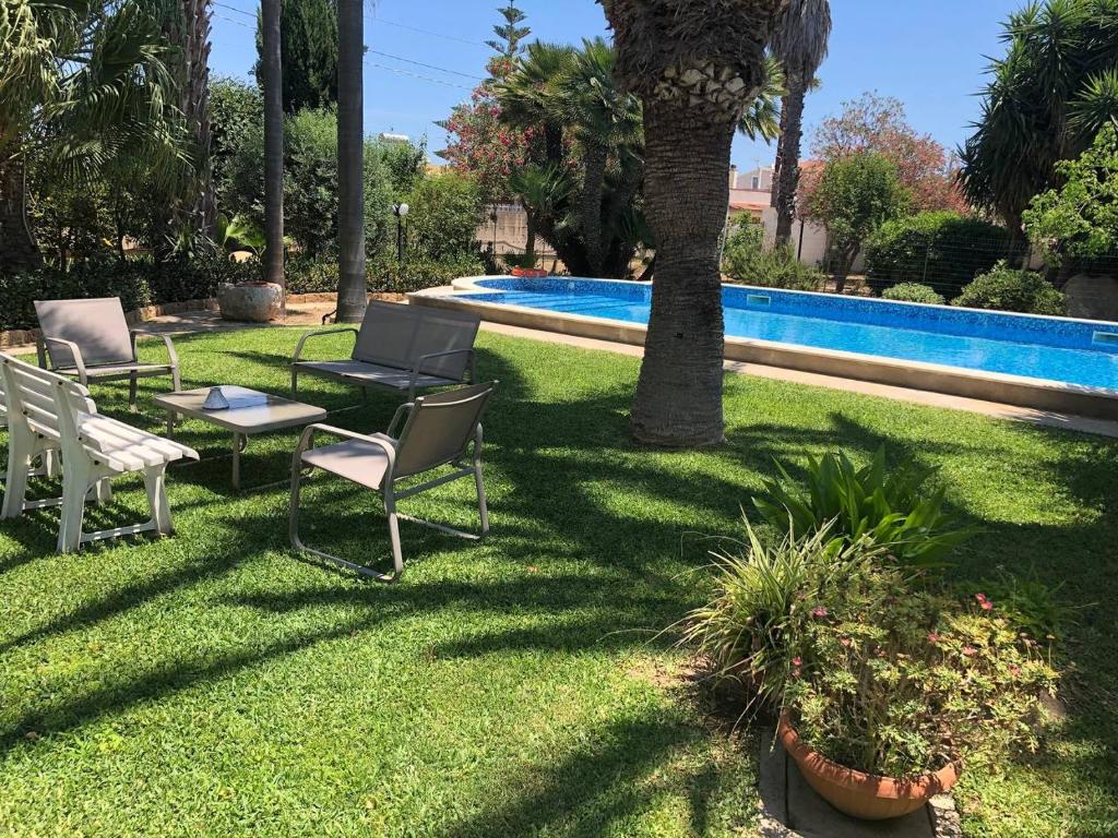 um quintal com cadeiras e uma mesa ao lado de uma piscina em Villa Yucca em Avola