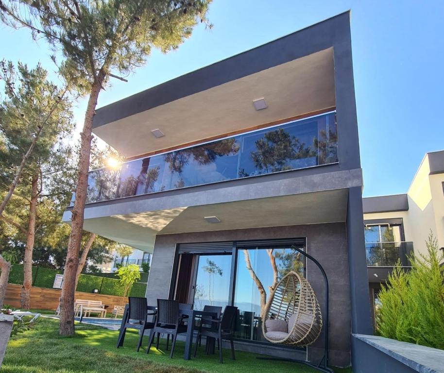 a glass house with black chairs in front of it at Özel havuz ve deniz manzaralı yeni villa in Kusadası