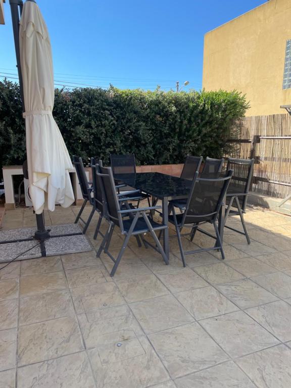 uma mesa e cadeiras com um guarda-sol e uma mesa em Sebastiano. Appartamento a 1,2 km dallo Stagnone em Marsala