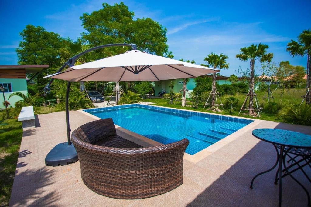 a swimming pool with a table and an umbrella at Me and Tree Villa in Kaeng Khoi