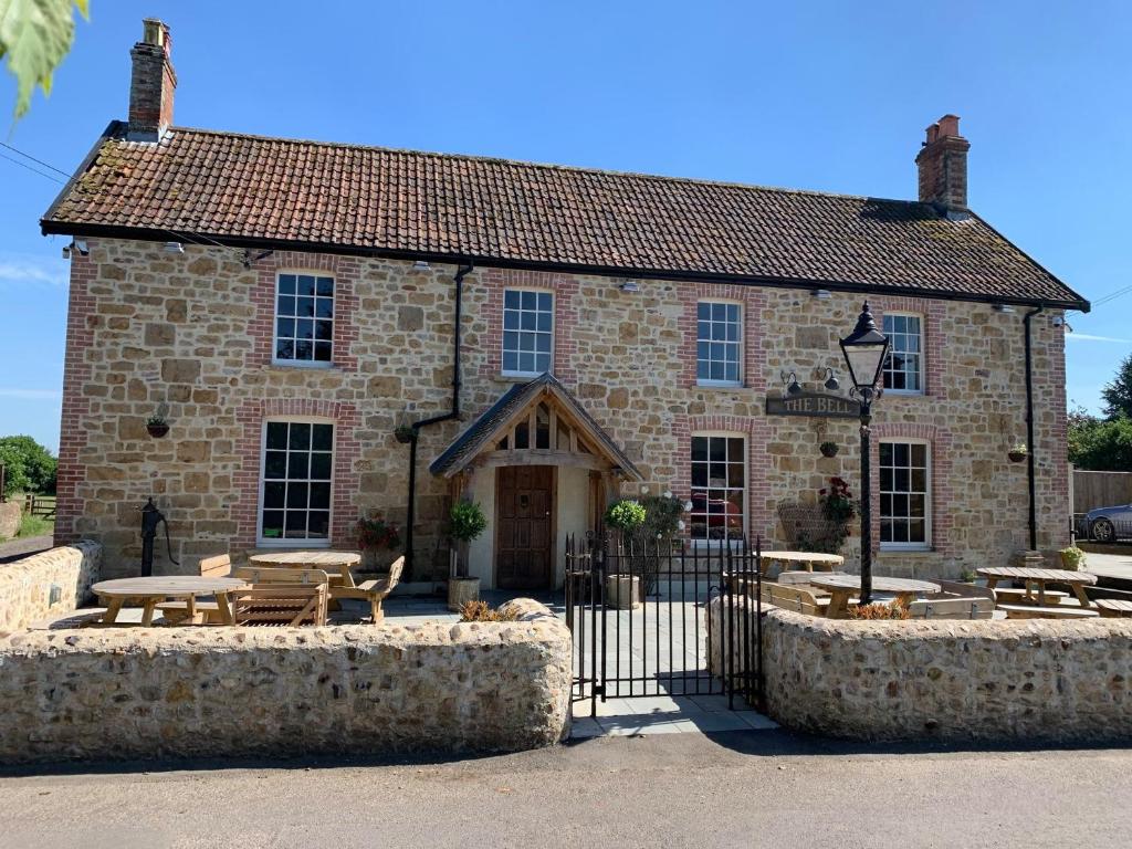 a stone building with tables and benches in front of it at The Bell Broadway in Broadway