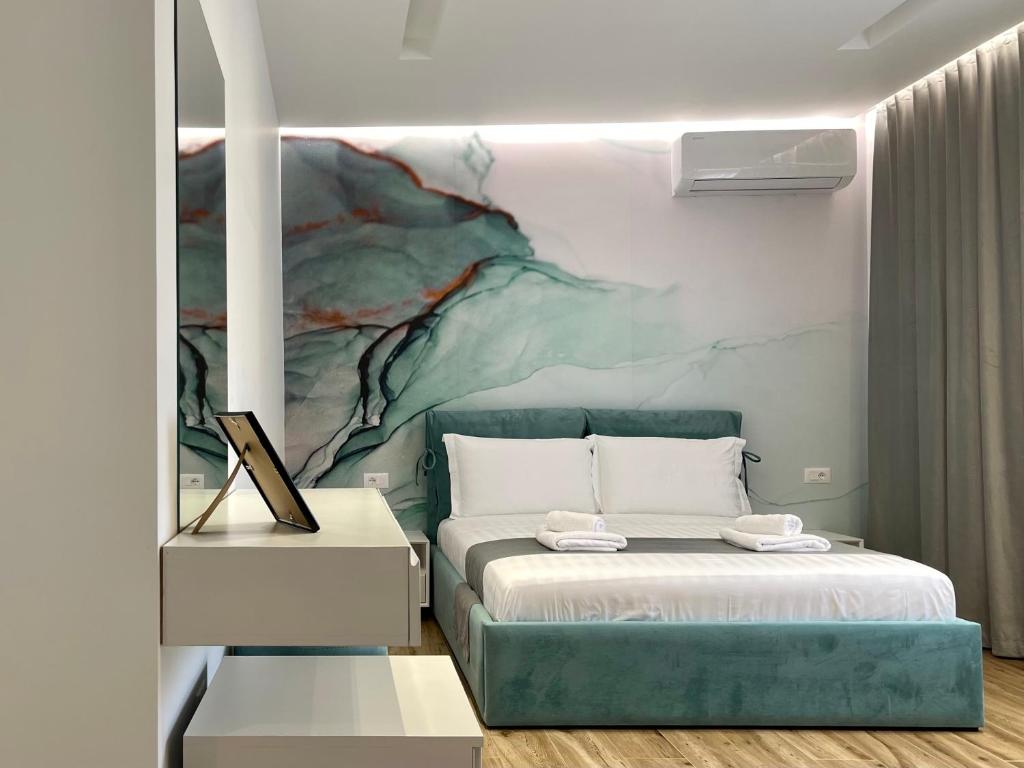 een slaapkamer met een bed en een schilderij aan de muur bij Vila Llanaj in Ksamil