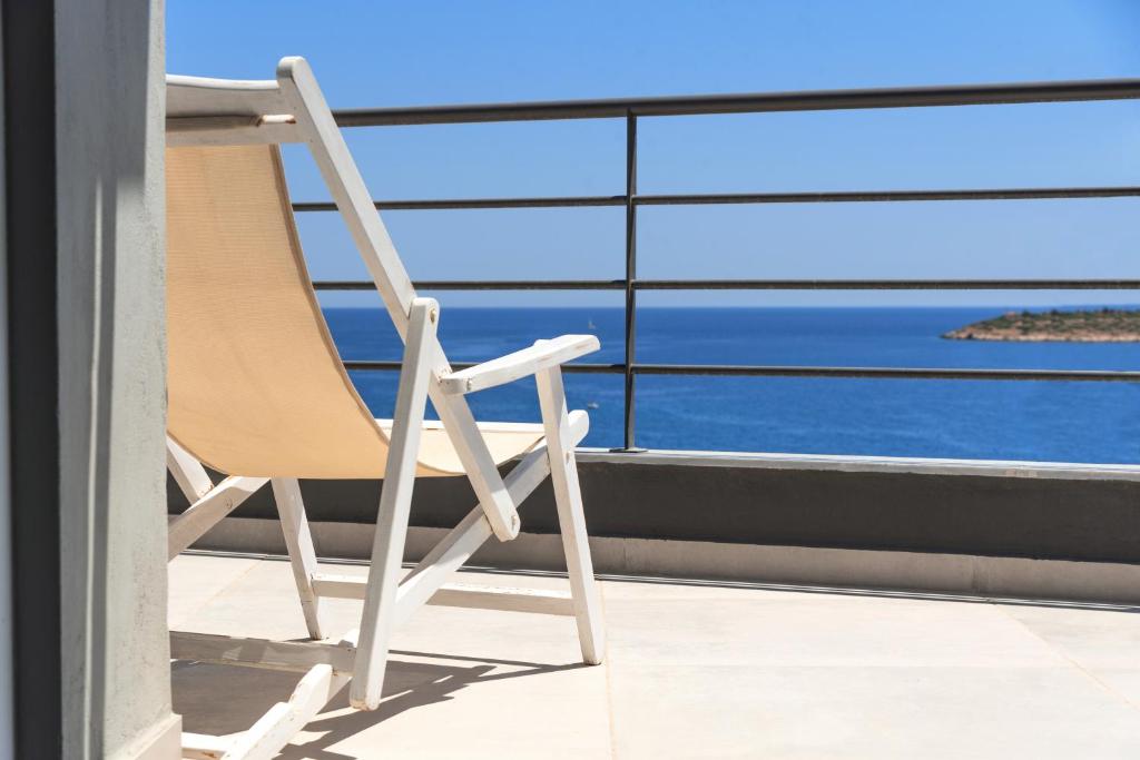 uma cadeira sentada numa varanda com vista para o oceano em CasaDeMar em Agios Nikolaos