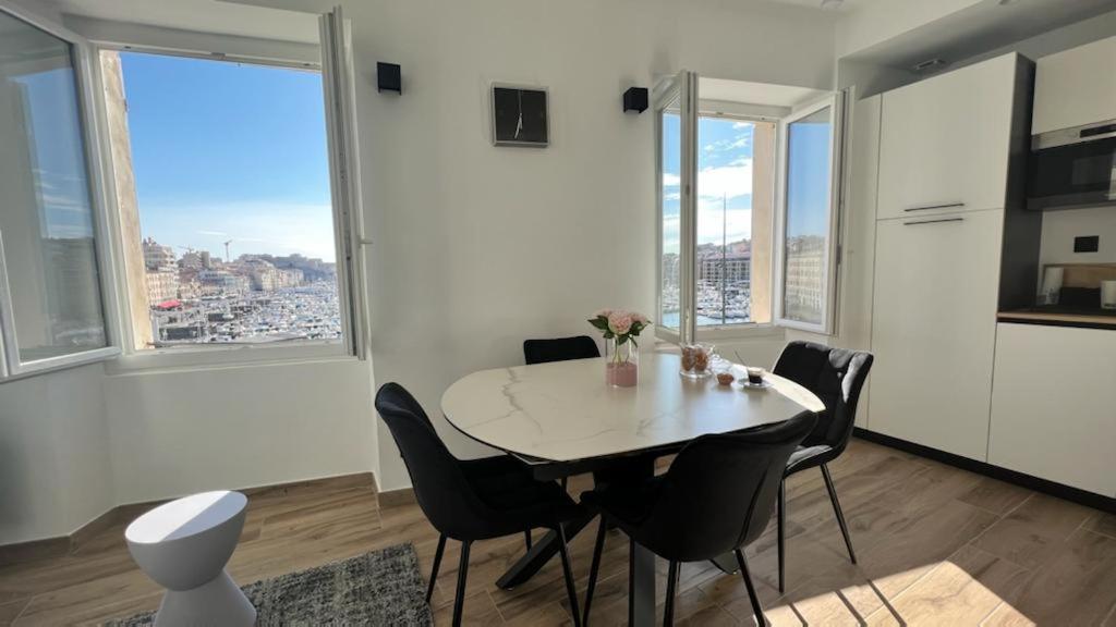 a dining room with a table and chairs and windows at Face au Vieux Port Vue 180 de Notre Dame au Panier in Marseille