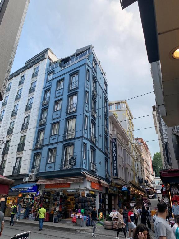 イスタンブールにあるギュルハネ コーナー ホテルの人の多い街路の青い建物