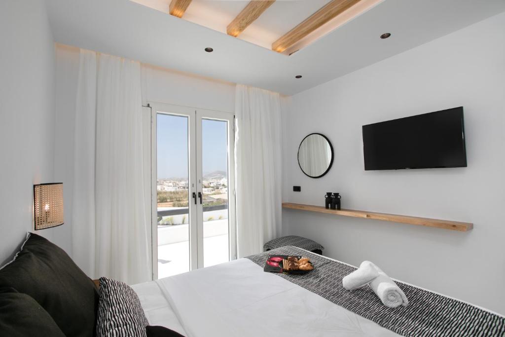 a bedroom with a bed with a television on the wall at Naxos White Concept in Naxos Chora