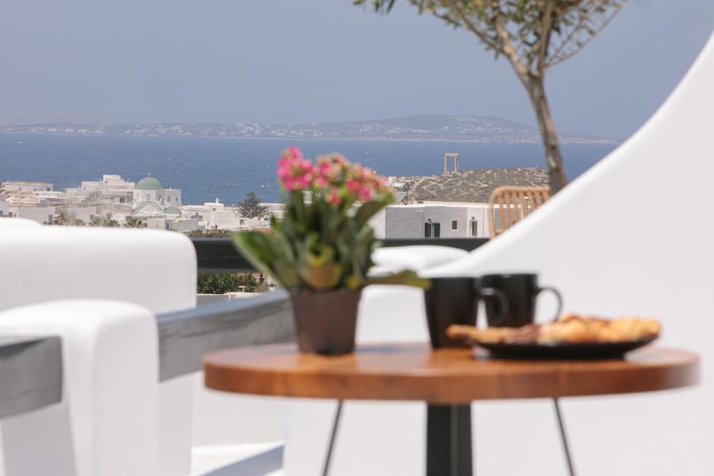 stół z talerzem jedzenia i kwiatów na balkonie w obiekcie Naxos White Concept w mieście Naksos