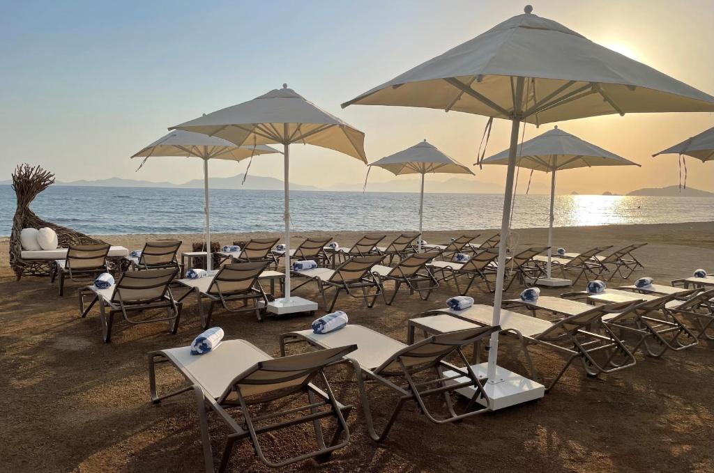 a group of tables and chairs with umbrellas on the beach at Rammos Managed By Dedeman in Bodrum City