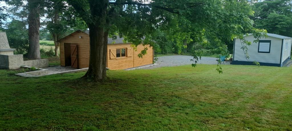 une cabane dans une cour avec un arbre dans l'établissement Vacances a la campagne mobil home tout confort , chalet avec barbecue,, à Javron-Les-Chapelles