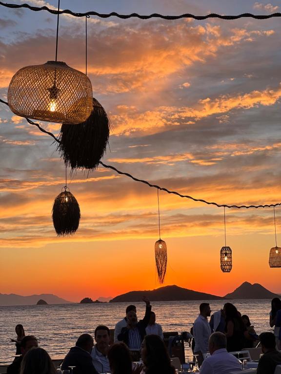 a group of people sitting at a table watching the sunset at Rammos Managed By Dedeman in Bodrum City