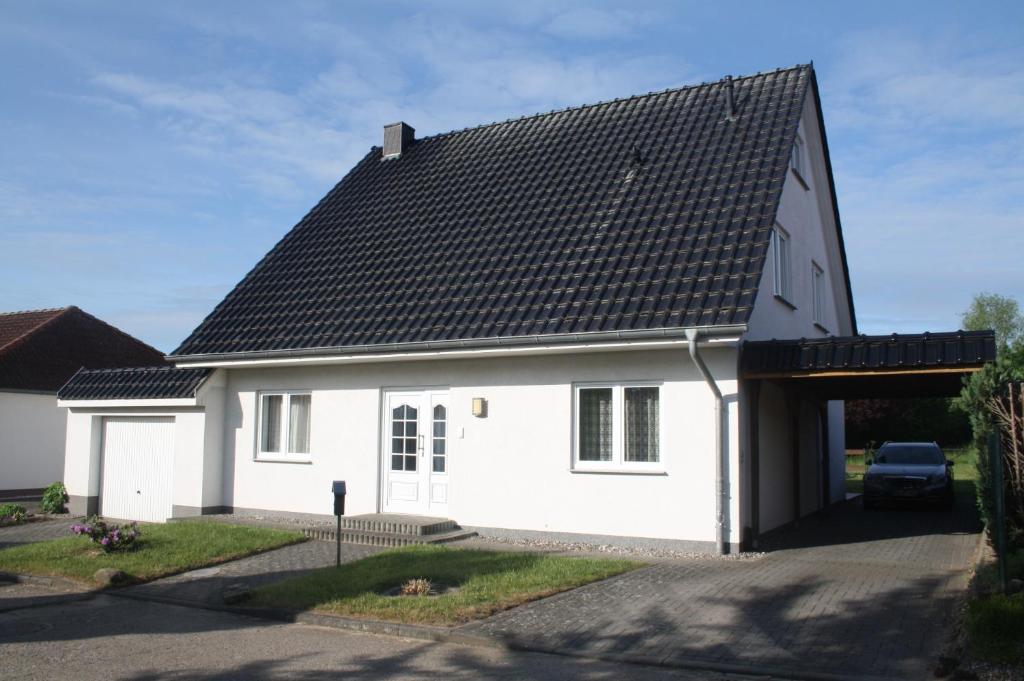 ein weißes Haus mit schwarzem Dach in der Unterkunft Wiesenblick in Loitz