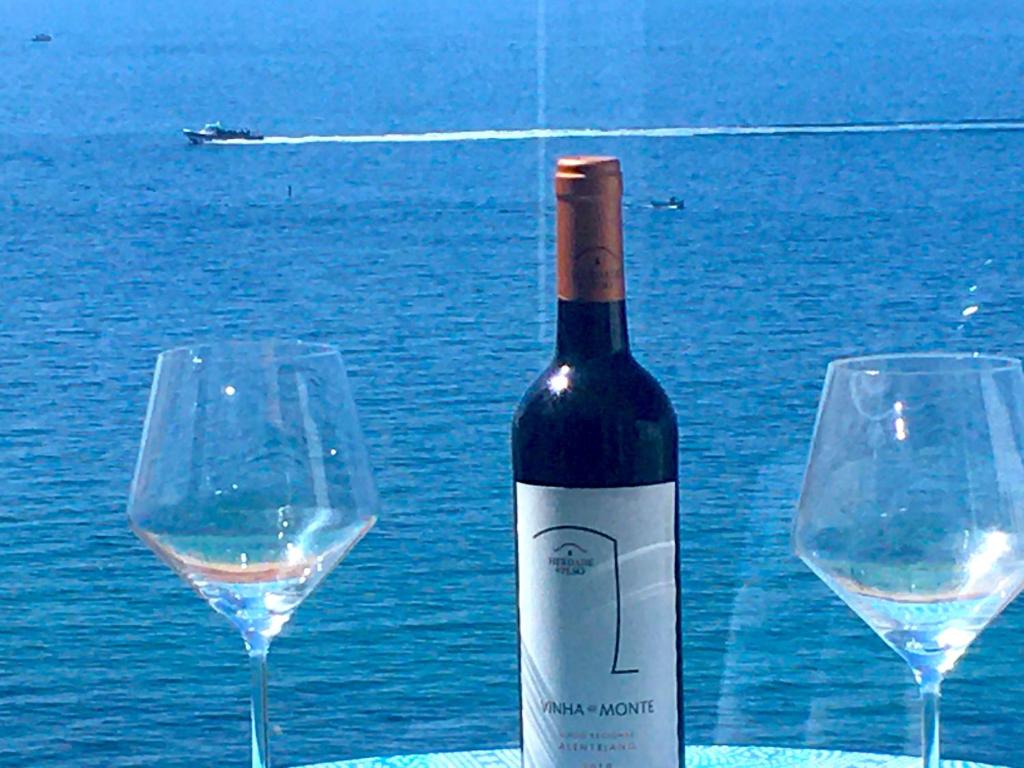 a bottle of wine sitting next to two wine glasses at O som das ondas - vista soberba de mar in Sesimbra