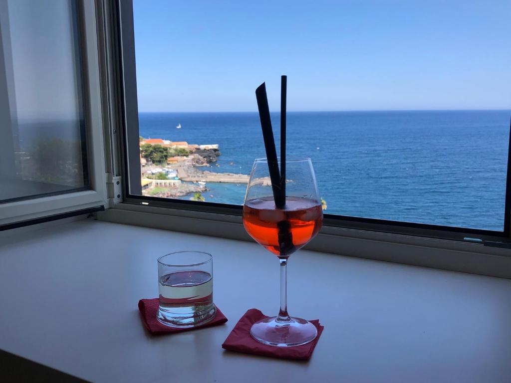 un drink in un bicchiere con una candela accanto a una finestra di Seascape Rooms a Catania