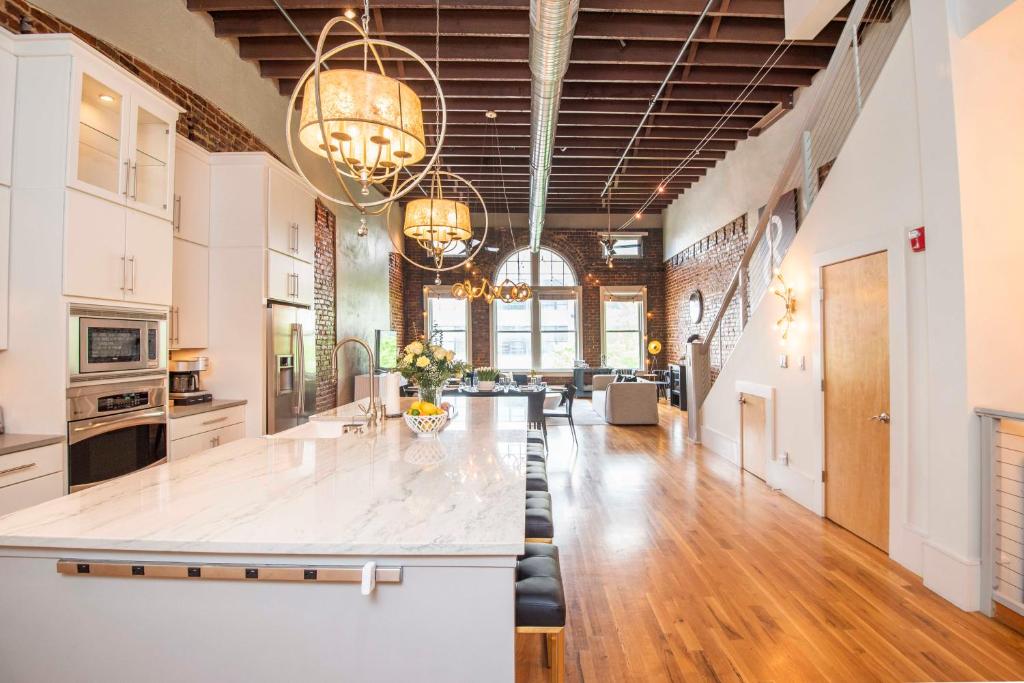 ノックスビルにあるLargest Rooftop w Firepit - Vaulted LUXE Penthouseのシャンデリアのあるオープンキッチンとリビングルーム