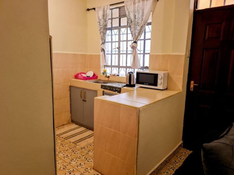 a small kitchen with a microwave on top of a counter at Cozy Spacious Studio Apartment close to Town in Nanyuki